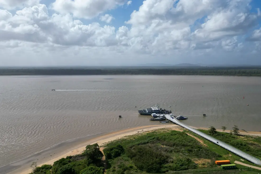 Vue aérienne du rivage du Mahury à Rémire-Montjoly : plage de sable, végétation et embarcadère sur l’eau ambrée