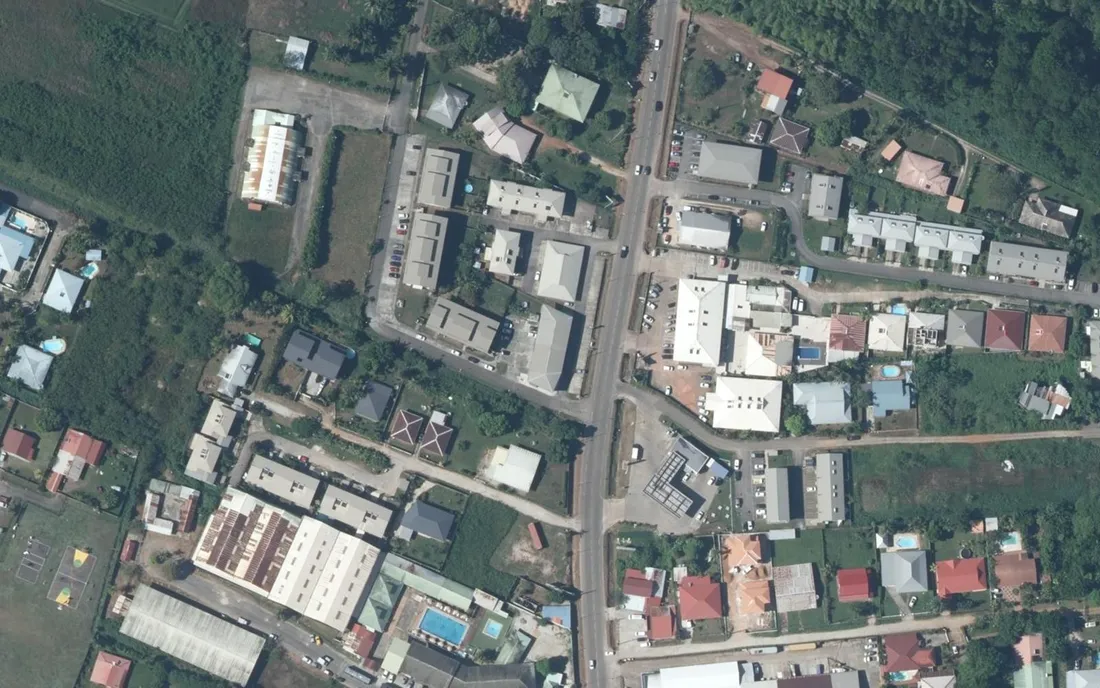 Vue aérienne verticale de petits immeubles d'habitation, de maisons individuelles et de commerces de part et d'autre de la route de Rémire, près du bourg de Rémire à Rémire-Montjoly (Guyane)