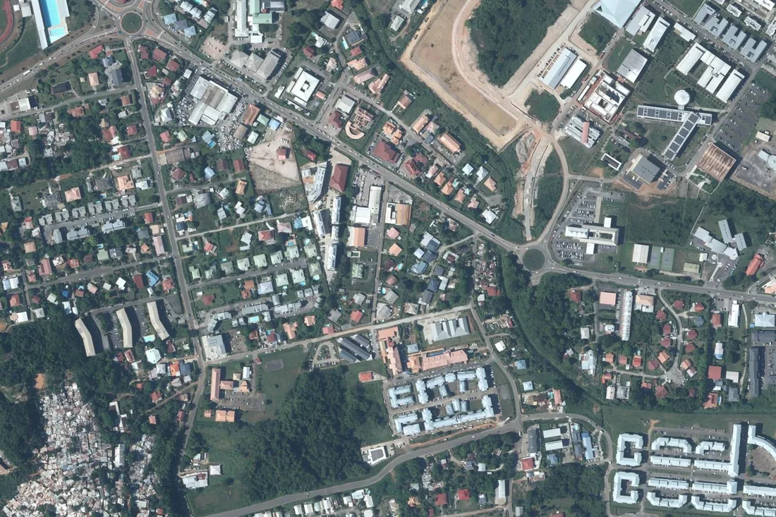 Vue aérienne verticale du secteur de Baduel à Cayenne : maisons individuelles, petits immeubles collectifs le long de la route de Baduel et campus de l'université de Guyane