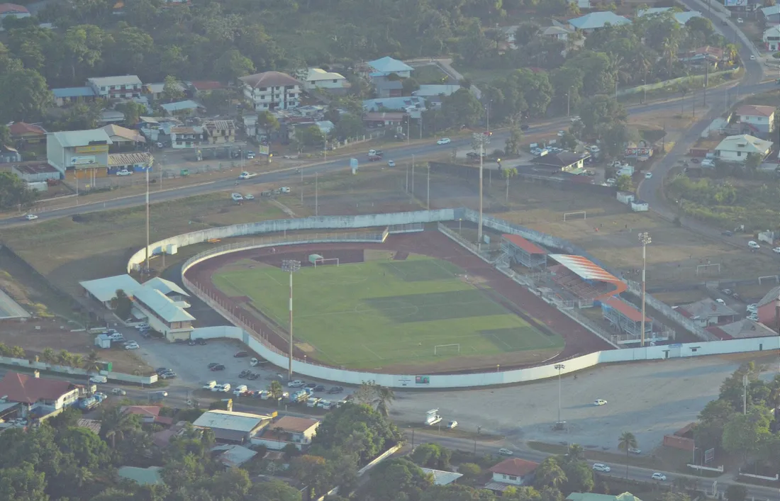 Photographie aérienne oblique du stade Georges-Chaumet de Baduel à Cayenne, entouré de maisons, de commerces et de la route de Baduel
