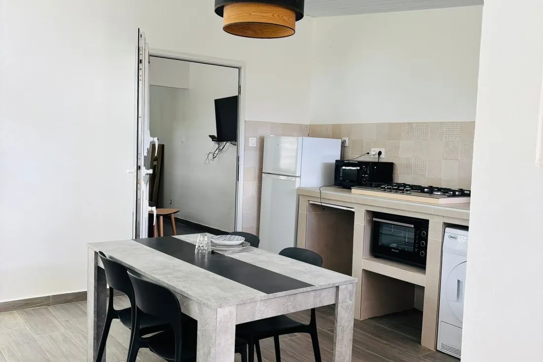 Coin repas et cuisine de la maison Tropikana avec table et chaises
