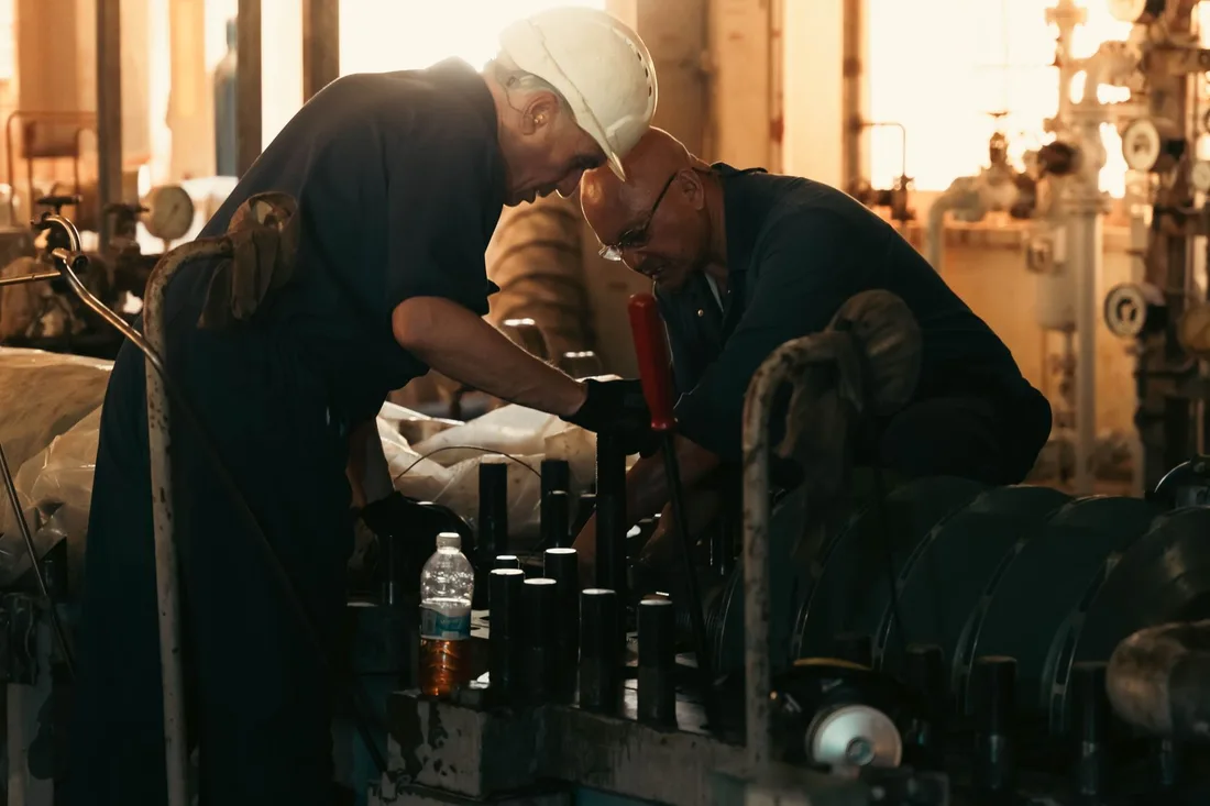 Deux techniciens intervenant ensemble sur une machine dans une installation industrielle