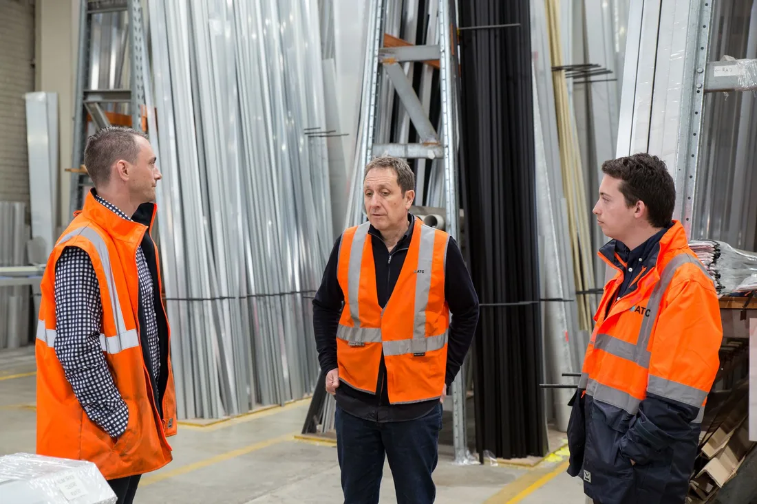Équipe en gilets haute visibilité échangeant dans un hangar industriel