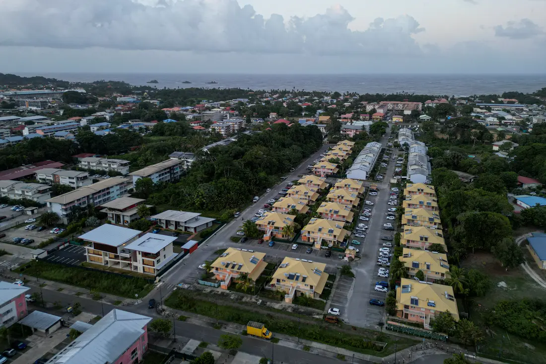 Résidence de la ZAC Hibiscus à Cayenne au crépuscule, bâtiments jaunes et voitures garées